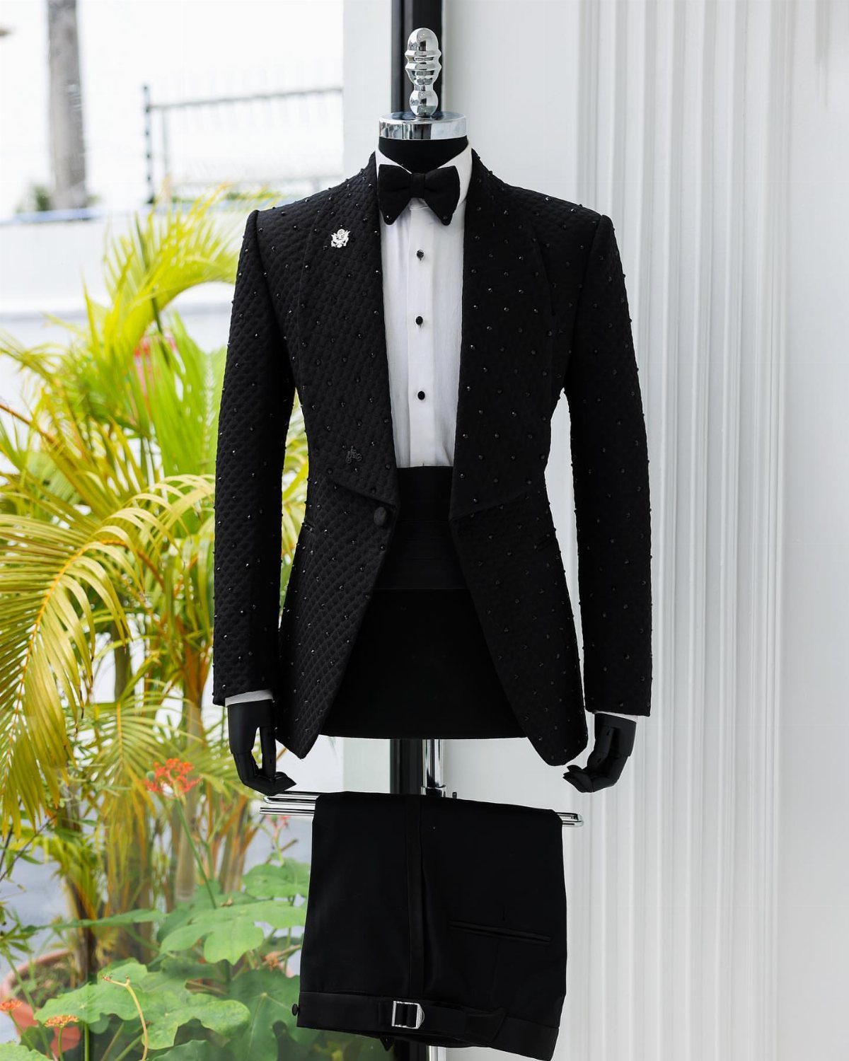Black jacquard patterned prom suit with a white shirt and bowtie on a mannequin.