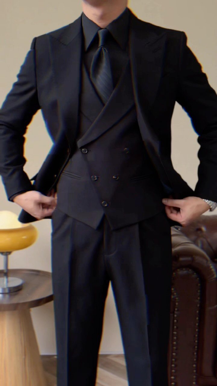 Man wearing a formal black three-piece suit with a black shirt and black tie.