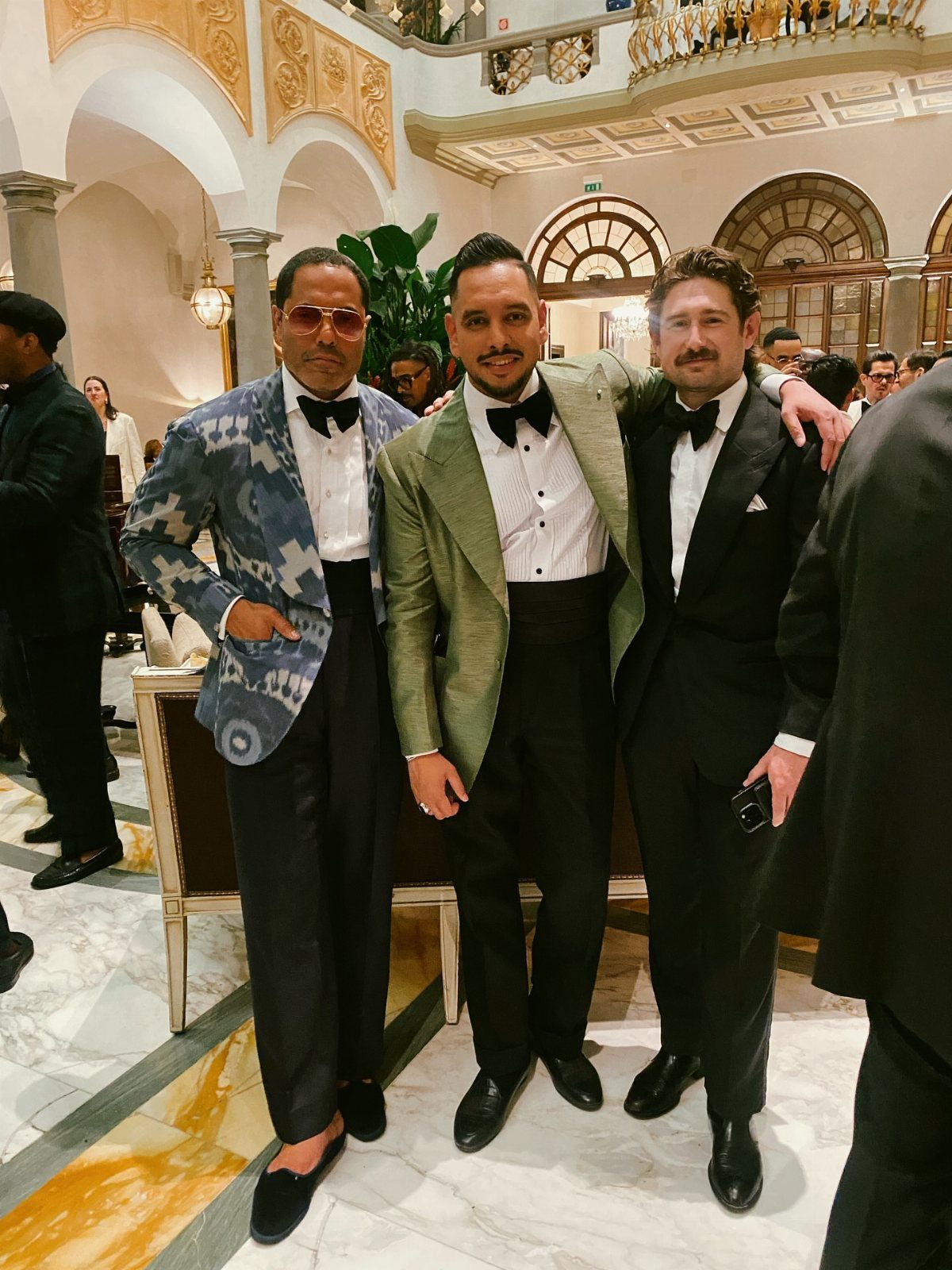 Three men posing in formal attire, including one wearing a blue patterned statement dinner jacket.