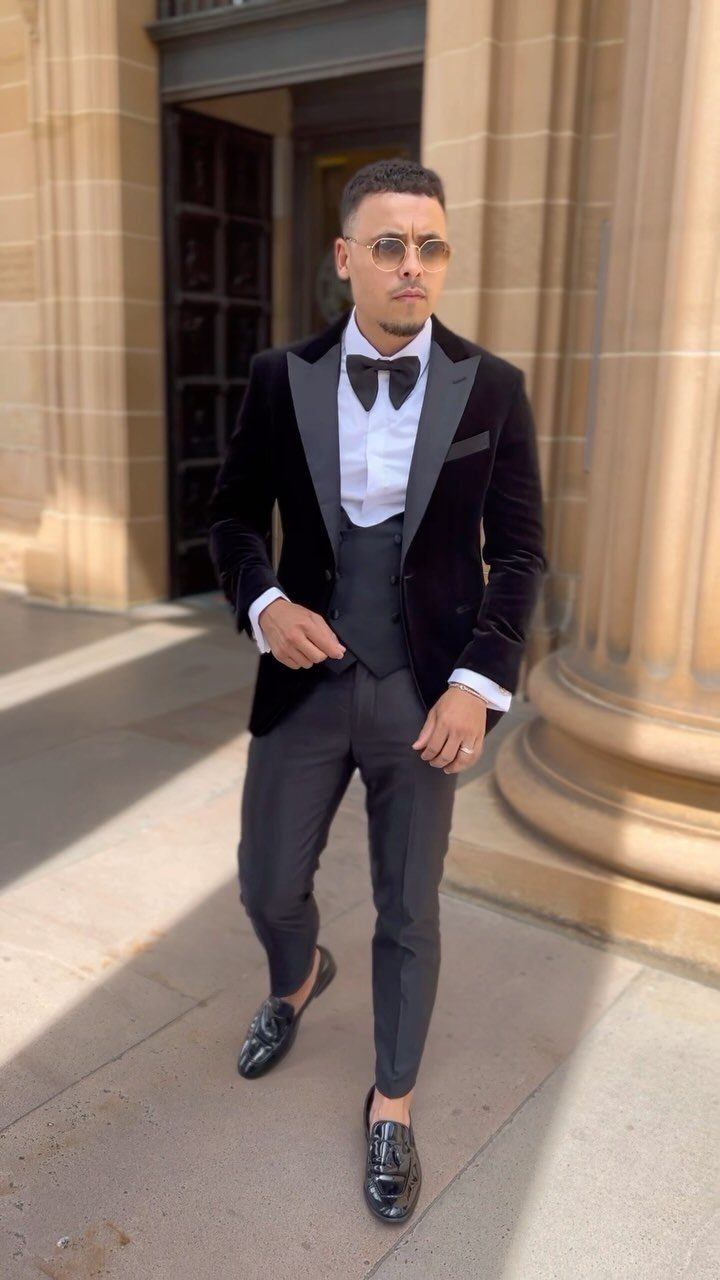 Man posing in a black velvet dinner jacket, white shirt, and black bow tie.