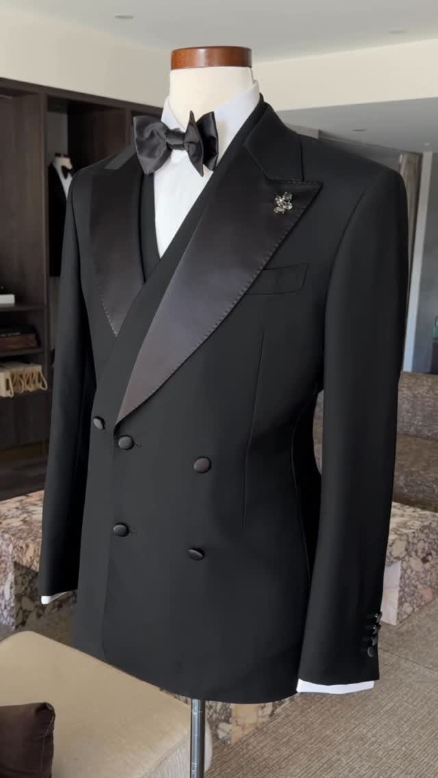 Black double-breasted tuxedo jacket with wide satin peak lapels on a mannequin.