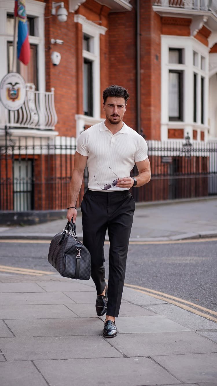 Man in a white polo shirt and black trousers walking through a city street.