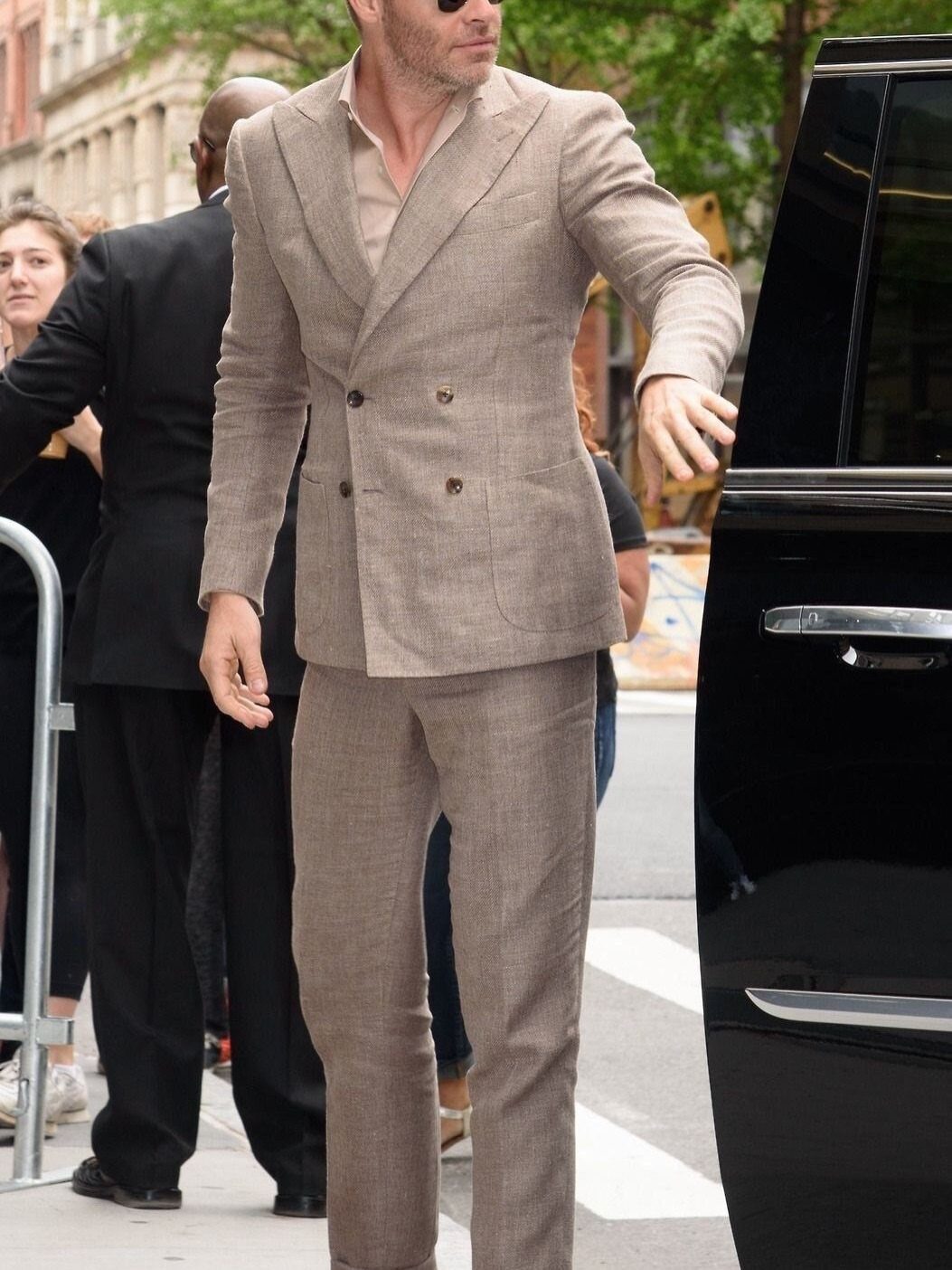 Man walking in a light brown double-breasted linen suit and beige shirt.
