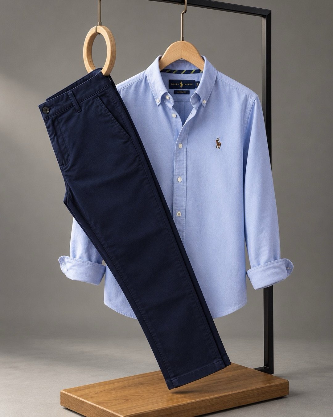 A light blue long-sleeved shirt and navy blue trousers hanging on a black clothing rack.