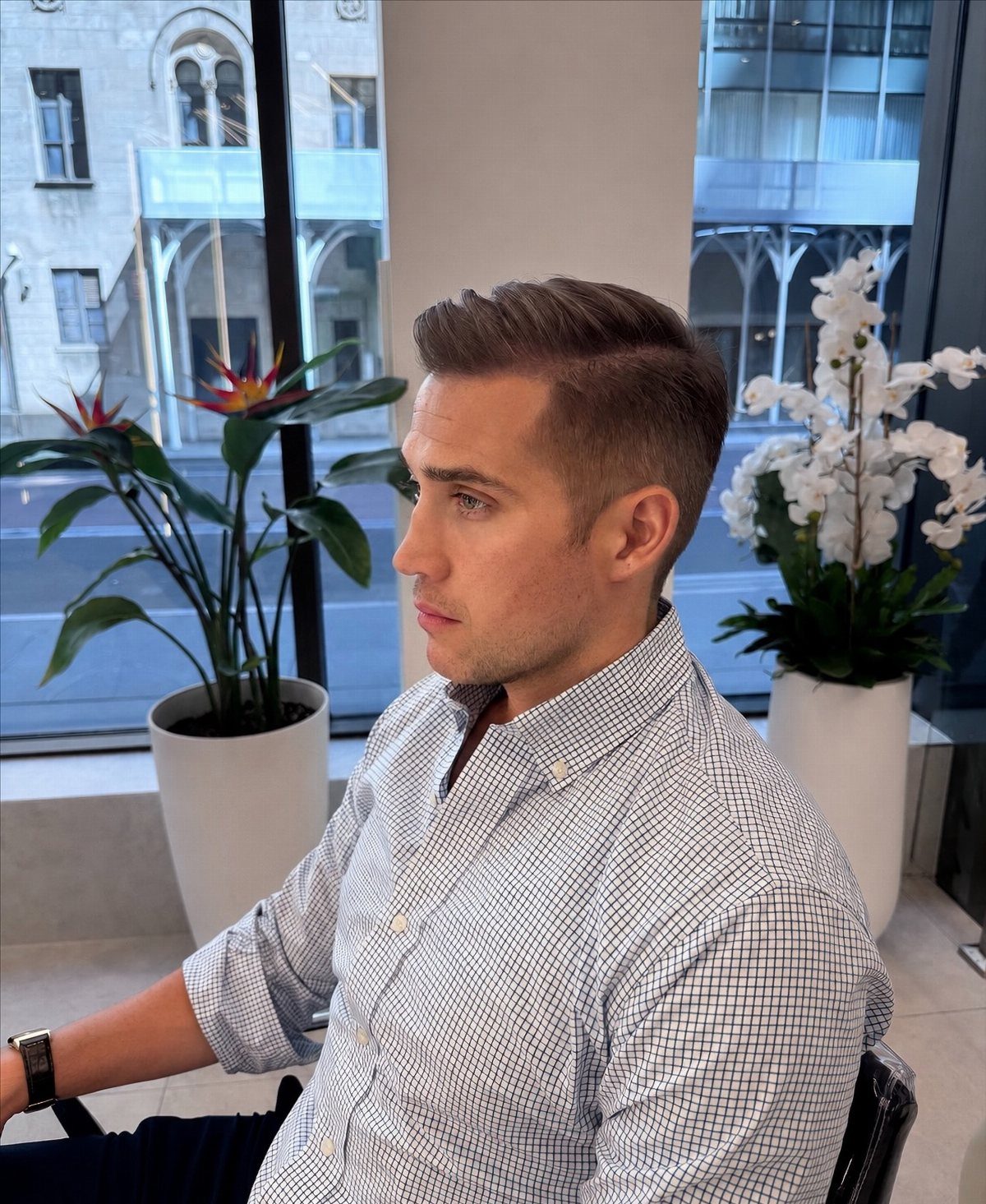 A young man with neatly styled hair and a clean-shaven face looking to the side.