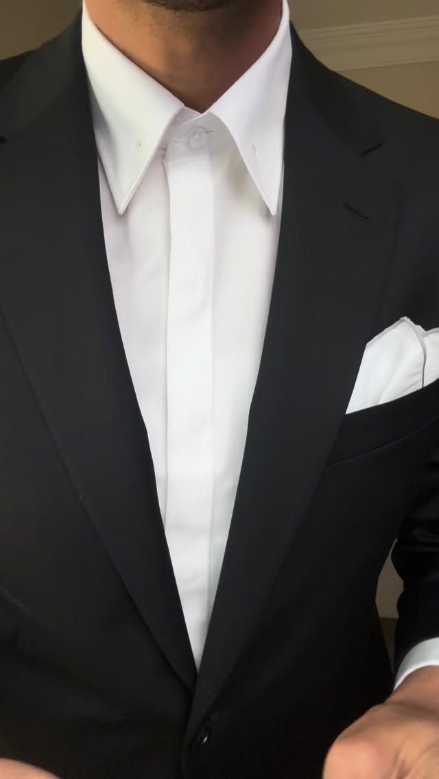 A man wearing a crisp white dress shirt and a black tailored blazer.