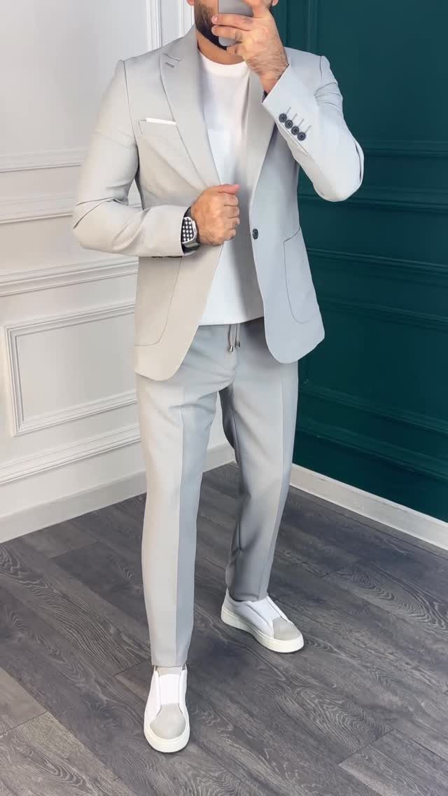 Man wearing a light grey suit with a white t-shirt and white sneakers.