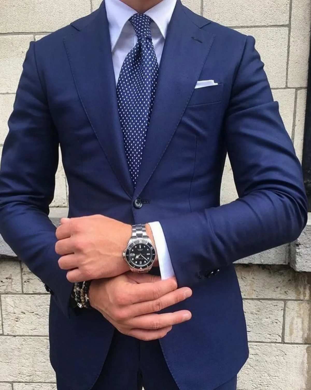 Man in a navy blue single-breasted suit with a notch lapel and polka dot tie.