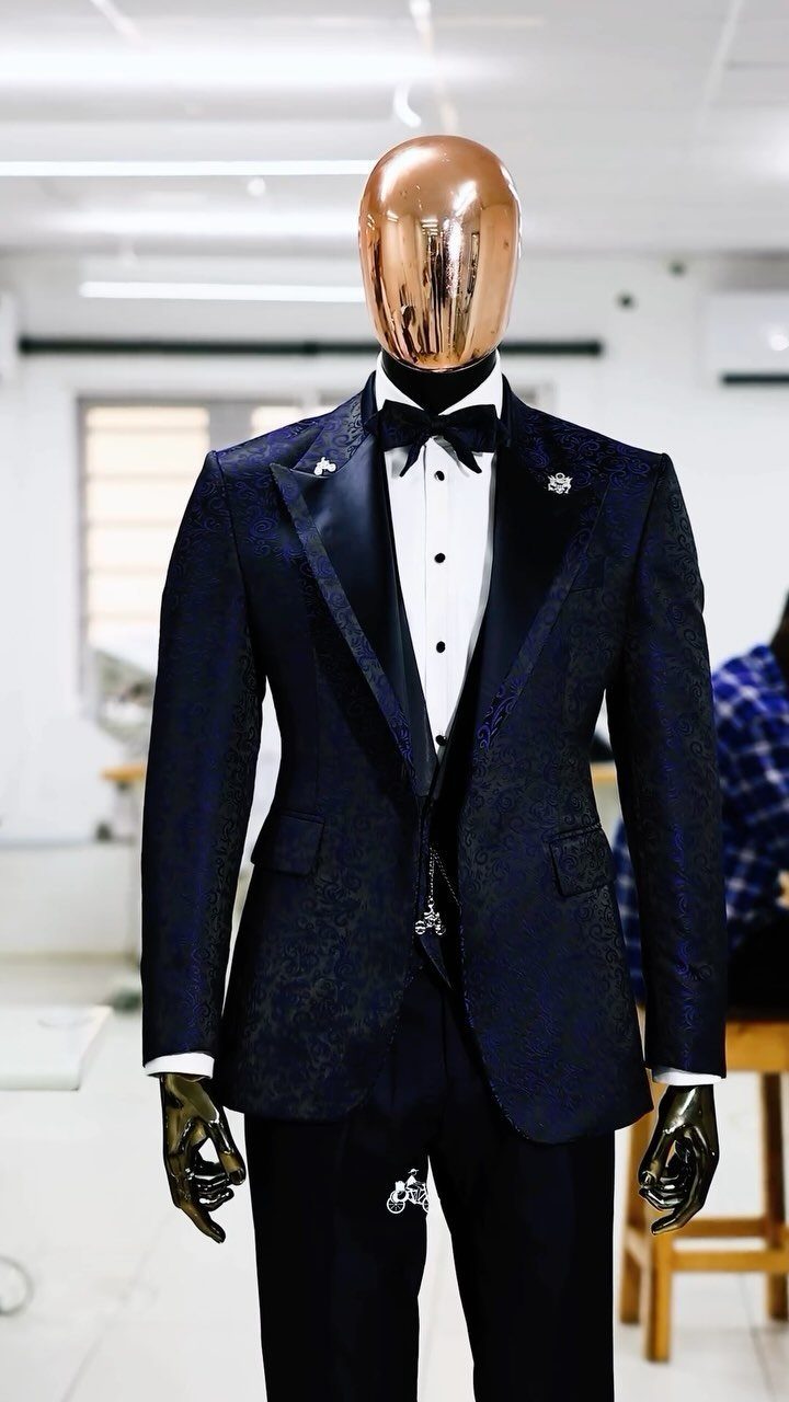 Navy blue patterned suit with peak lapels on a copper mannequin wearing a bowtie.