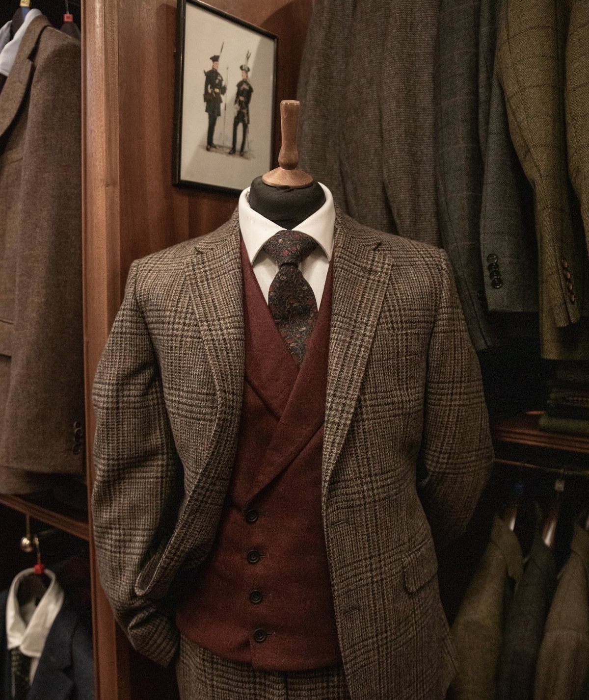 A mannequin wearing a brown plaid three-piece suit with a waistcoat and patterned tie.