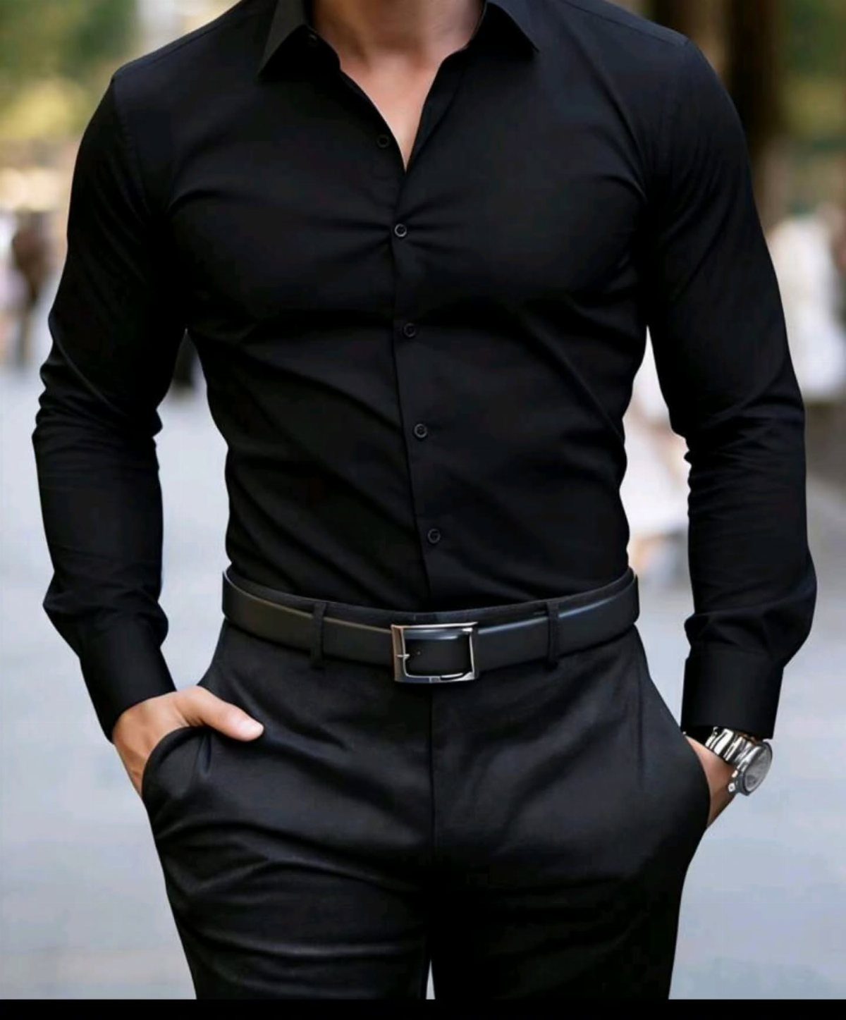 Man wearing a fitted black long-sleeve dress shirt and black trousers with a belt.