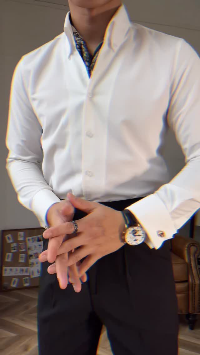 A man wearing a crisp white dress shirt with French cuffs and black trousers.