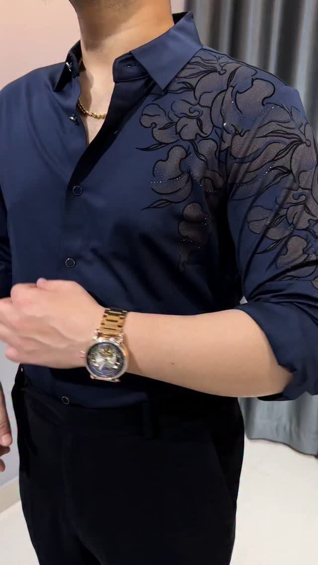 Man wearing a navy blue shirt with sheer floral embroidery on the shoulder and sleeve.