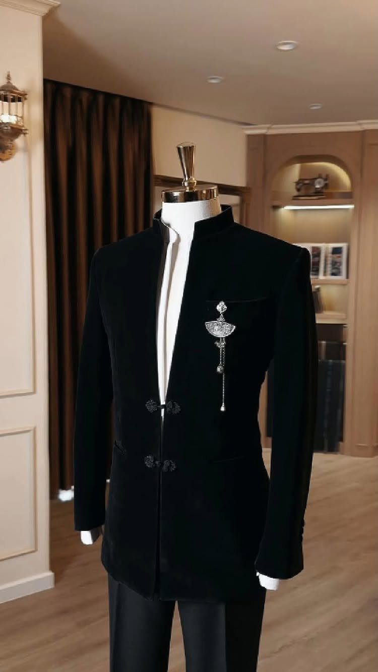 Black velvet mandarin collar jacket with a silver brooch displayed on a white mannequin.