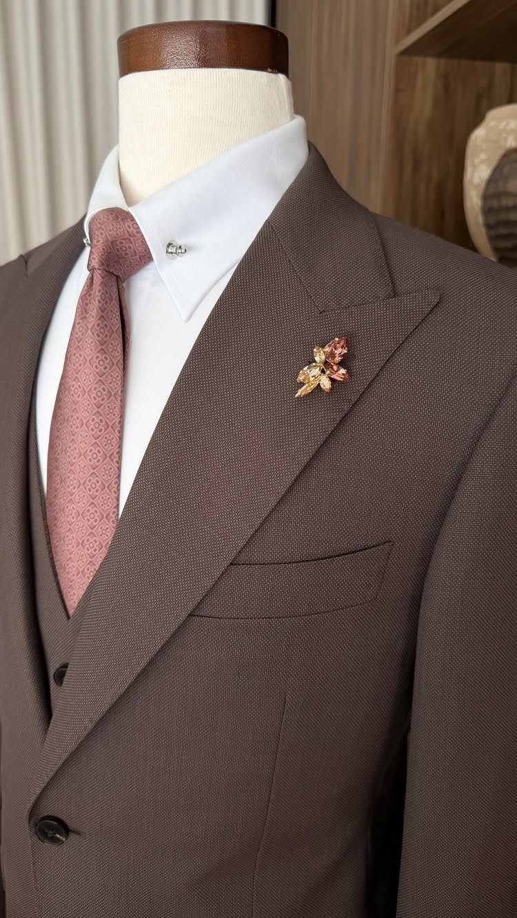Brown textured suit on a mannequin with a rose tie and gold lapel pin.