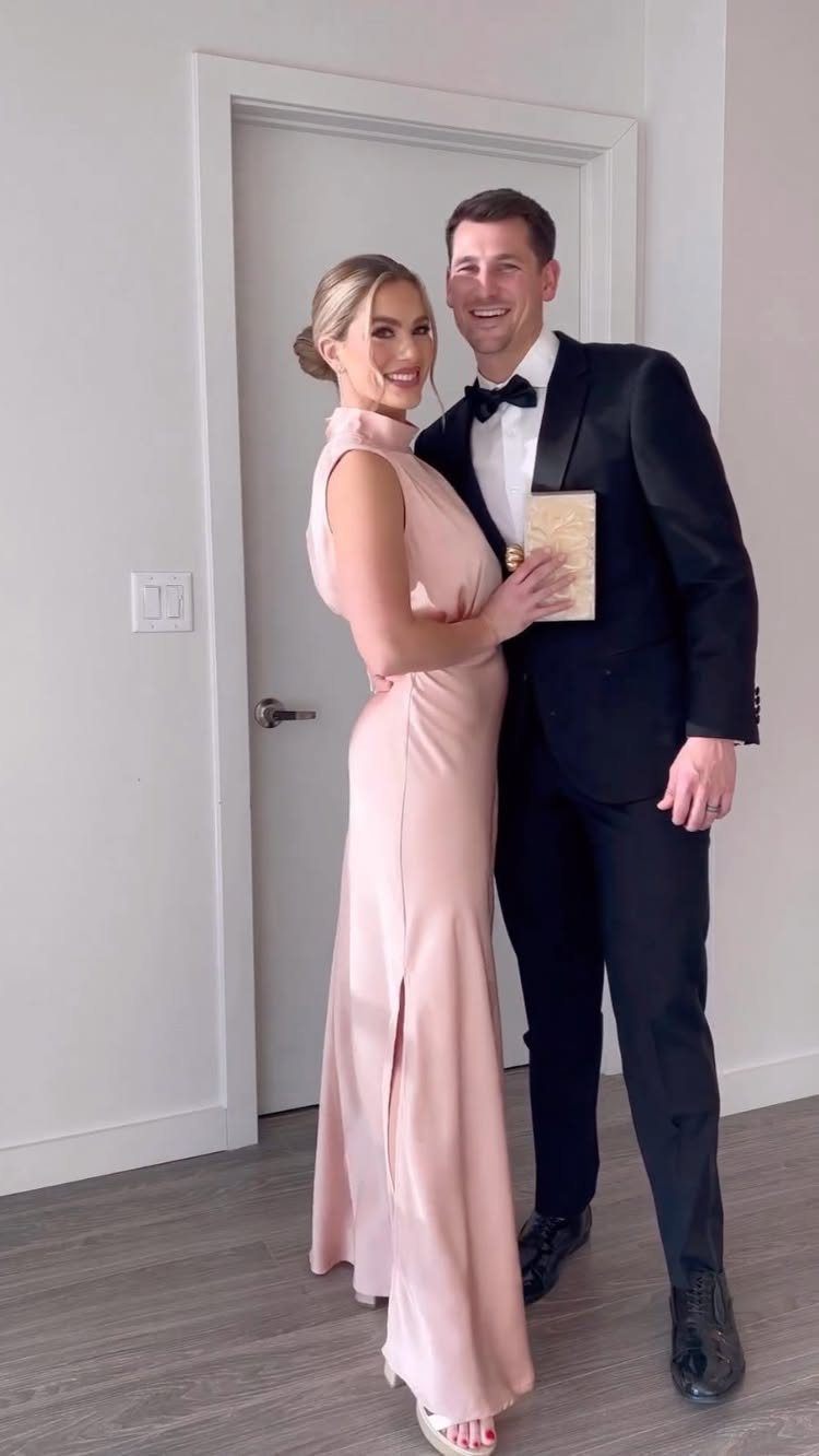 A man in a black tuxedo and a woman in a pink gown posing together.