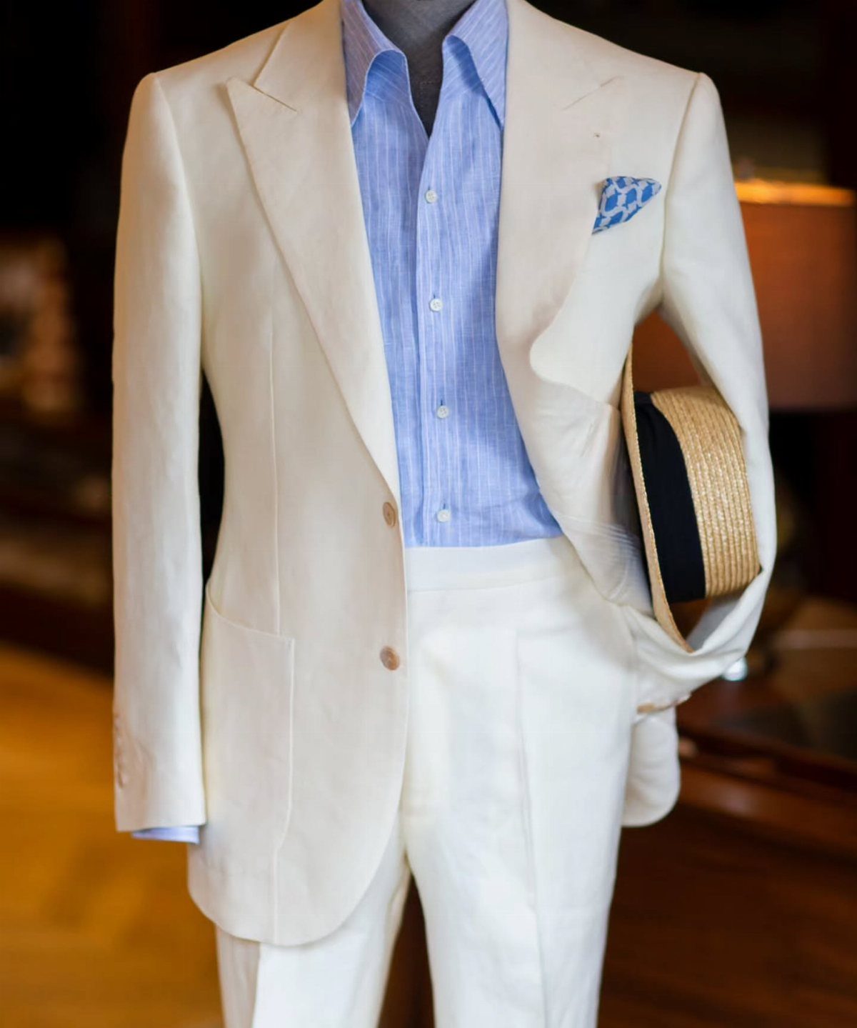 Cream linen suit on a mannequin with a blue shirt and straw hat.