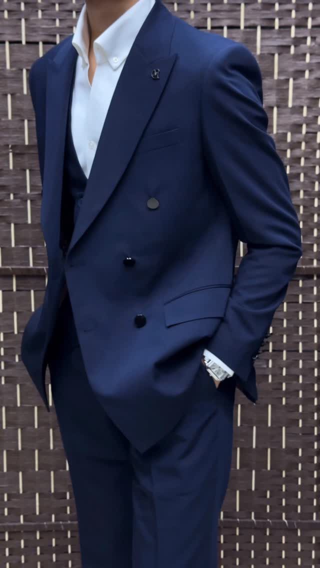 Man wearing a navy blue double-breasted suit and a white collared shirt.