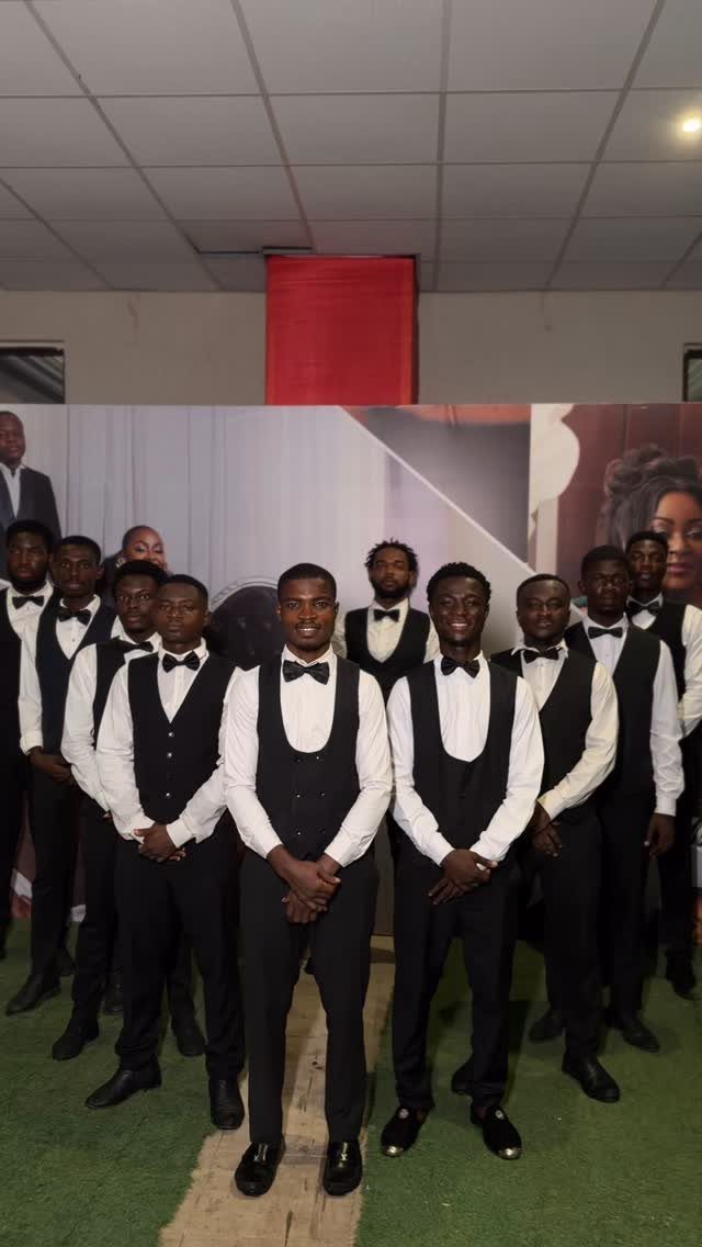 Men in matching black vests, white shirts, and black bow ties posing together.