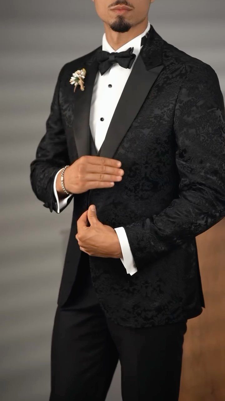 Man in a black patterned tuxedo jacket with a white shirt and black bow tie.