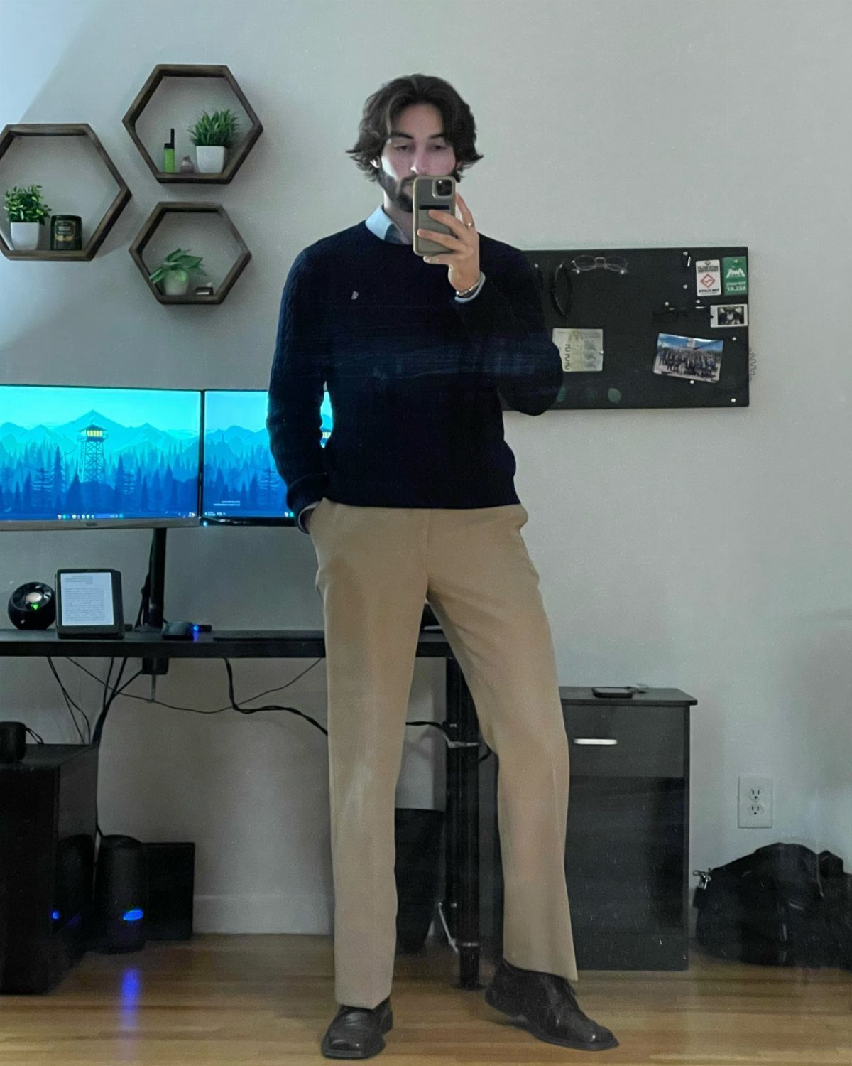 Man in a dark blue sweater and tan chinos posing for a mirror selfie.