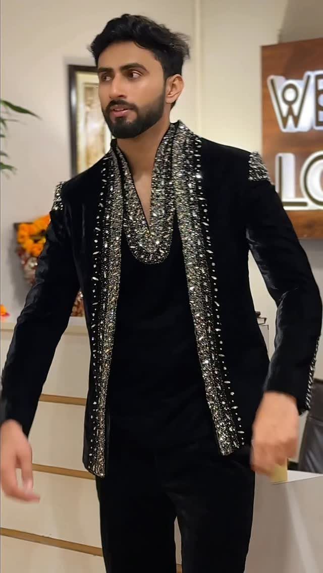 Man wearing a black velvet suit with elaborate silver sequin embellishments on the lapels.