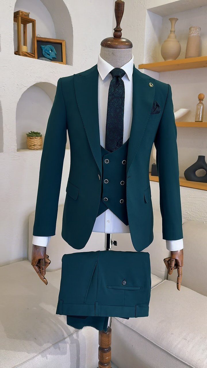 A dark teal three-piece suit displayed on a mannequin with a white shirt and dark tie.