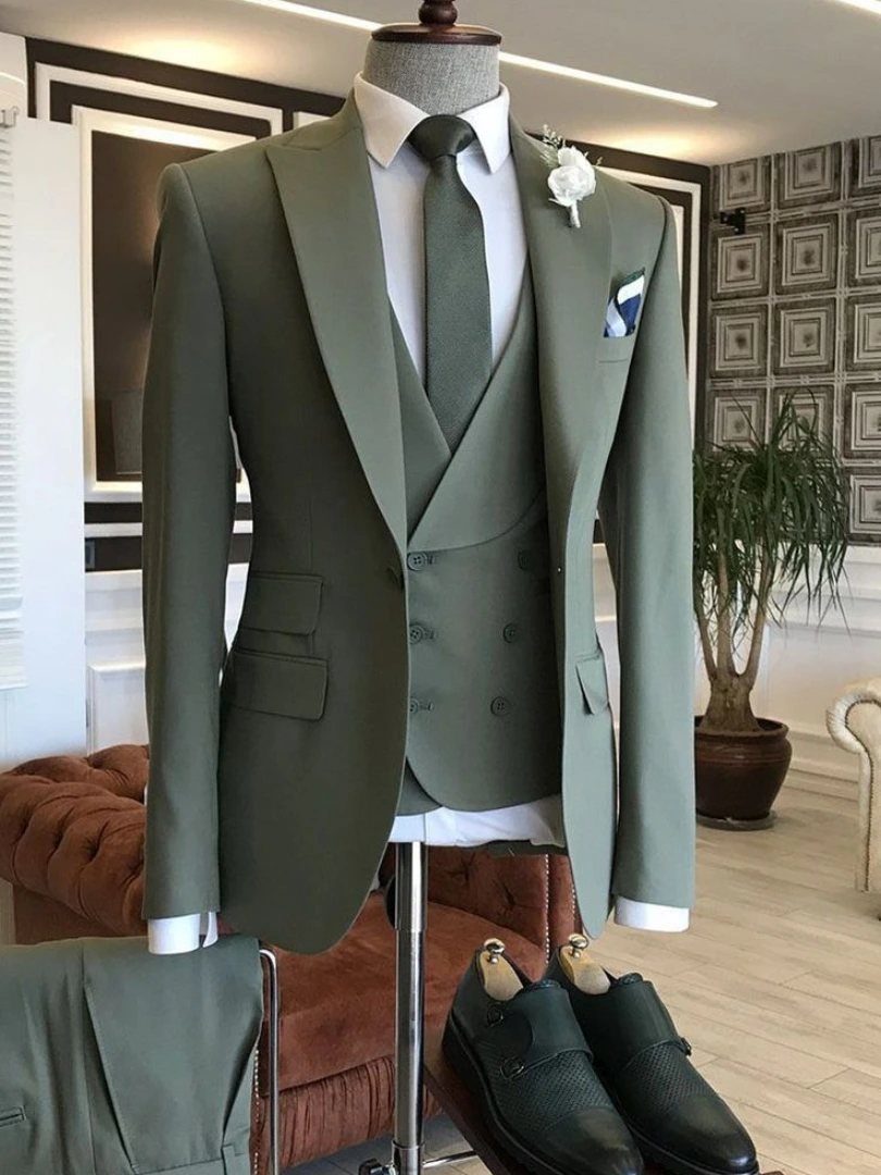 Sage green three-piece suit on a mannequin with a white boutonniere and black dress shoes.
