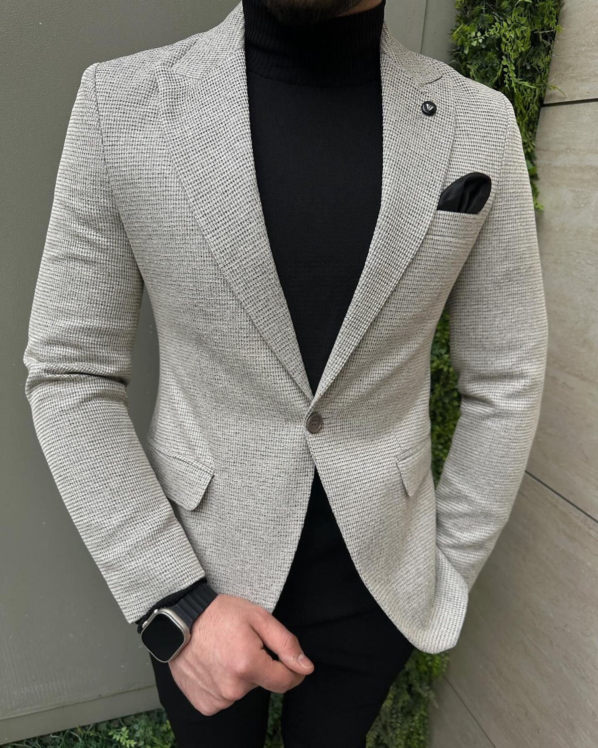Man wearing a light grey textured sport coat over a black turtleneck sweater.