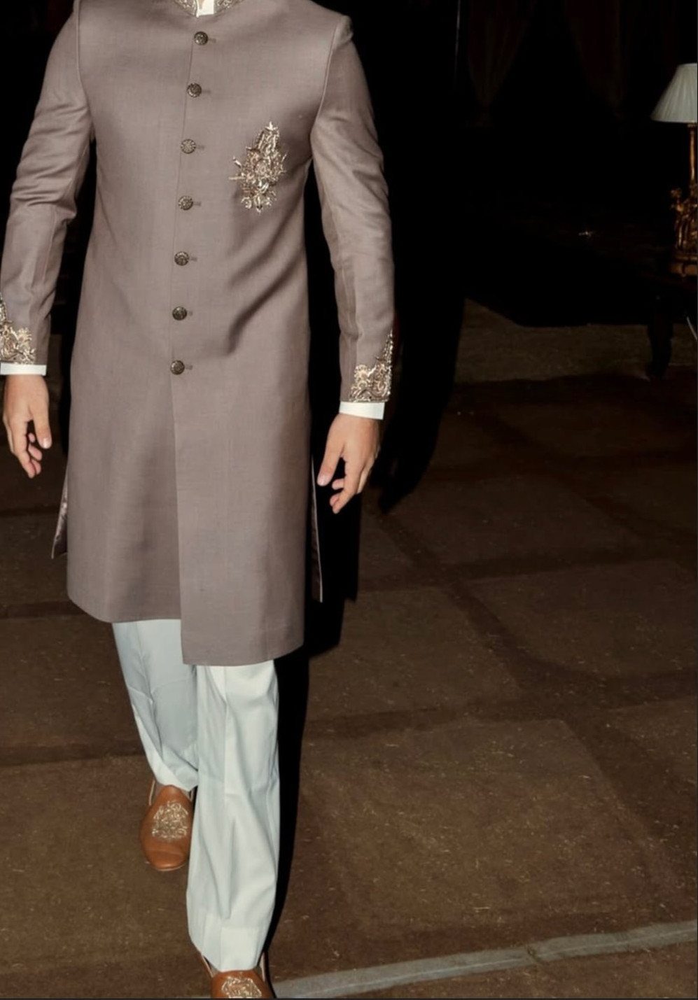 Man wearing a taupe Achkan with silver embroidery and light straight pants.