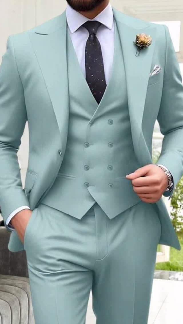 Man wearing a light mint green three-piece suit with a dark tie and boutonniere.
