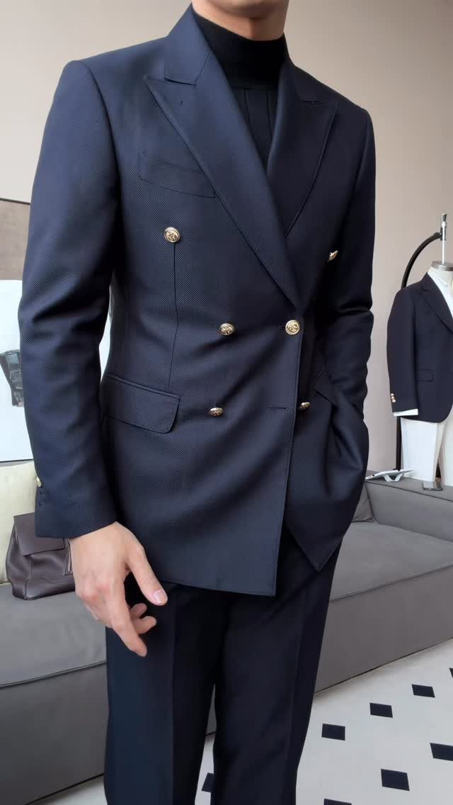 Man wearing a navy blue double-breasted blazer with gold buttons and matching trousers.