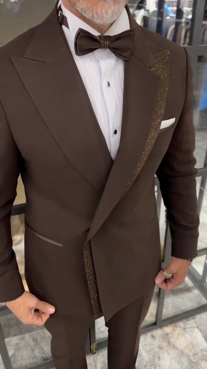 A man in a brown formal suit with gold glitter lapels and a matching bow tie.
