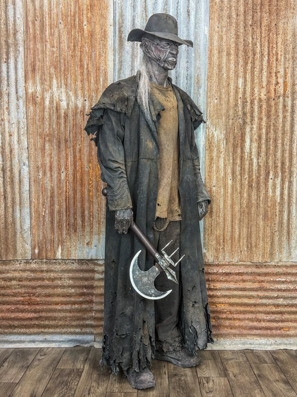 A person in a tattered dark cloak and wide-brimmed hat holding a large double-headed axe.