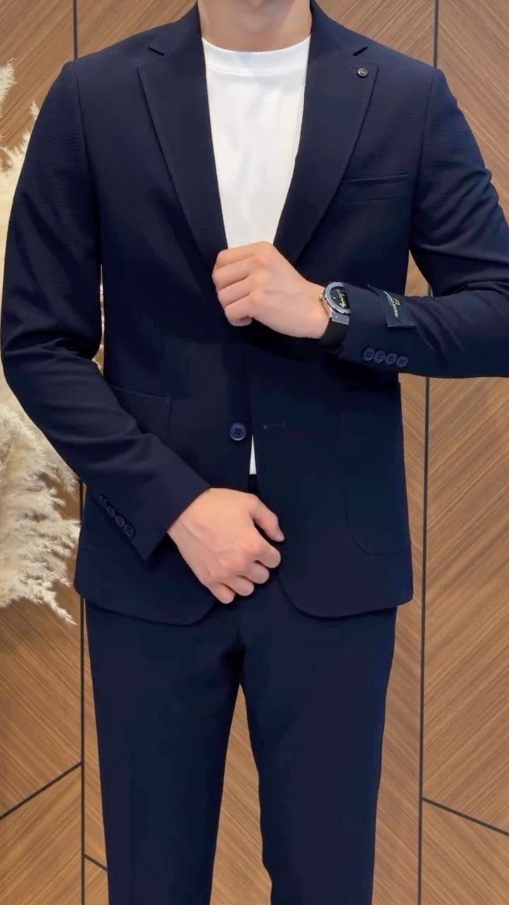 Man wearing a navy blue suit jacket paired with a white t-shirt and matching trousers.