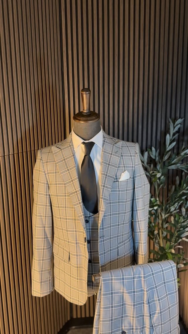 A light gray plaid suit with a dark tie and waistcoat on a mannequin.