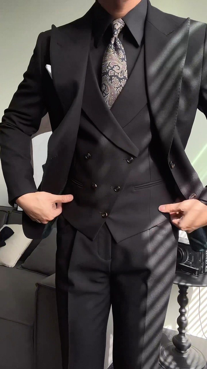 Man wearing a black double-breasted three-piece suit with a patterned tie.