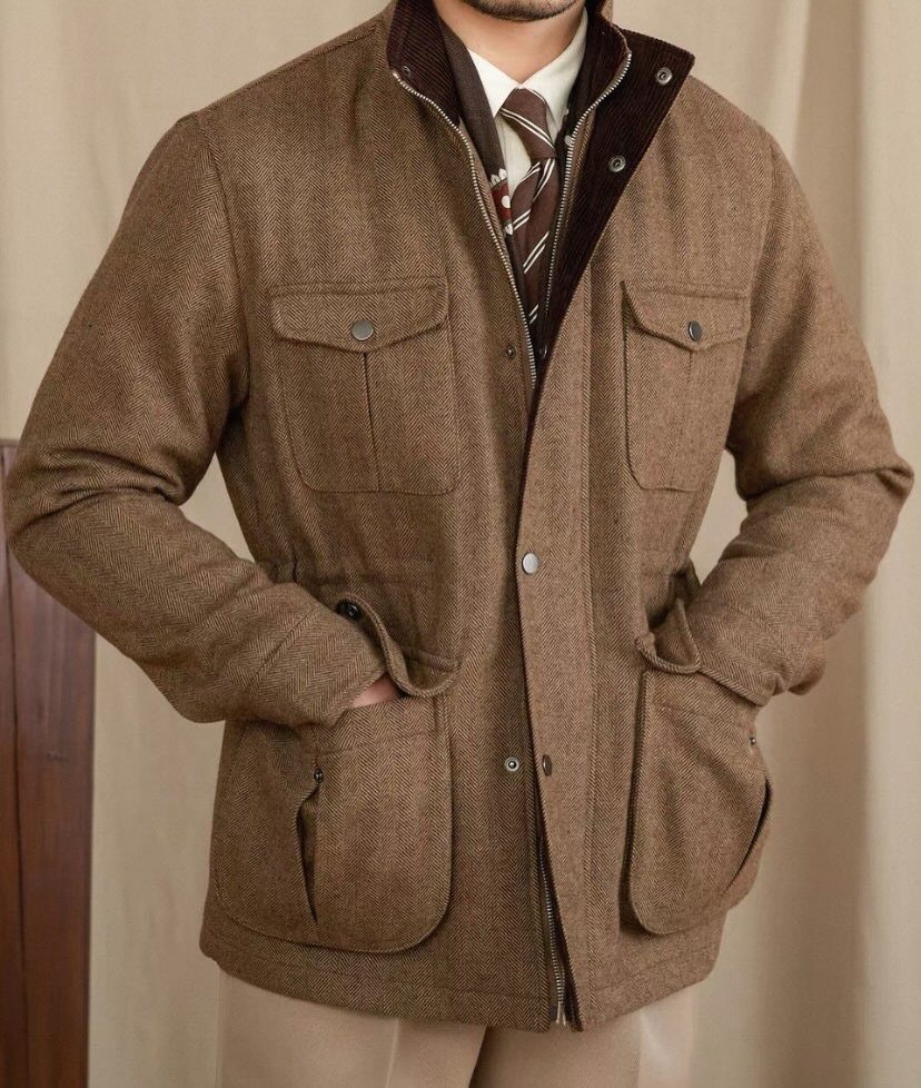 Man wearing a brown textured field jacket with large pockets over a sweater and tie.