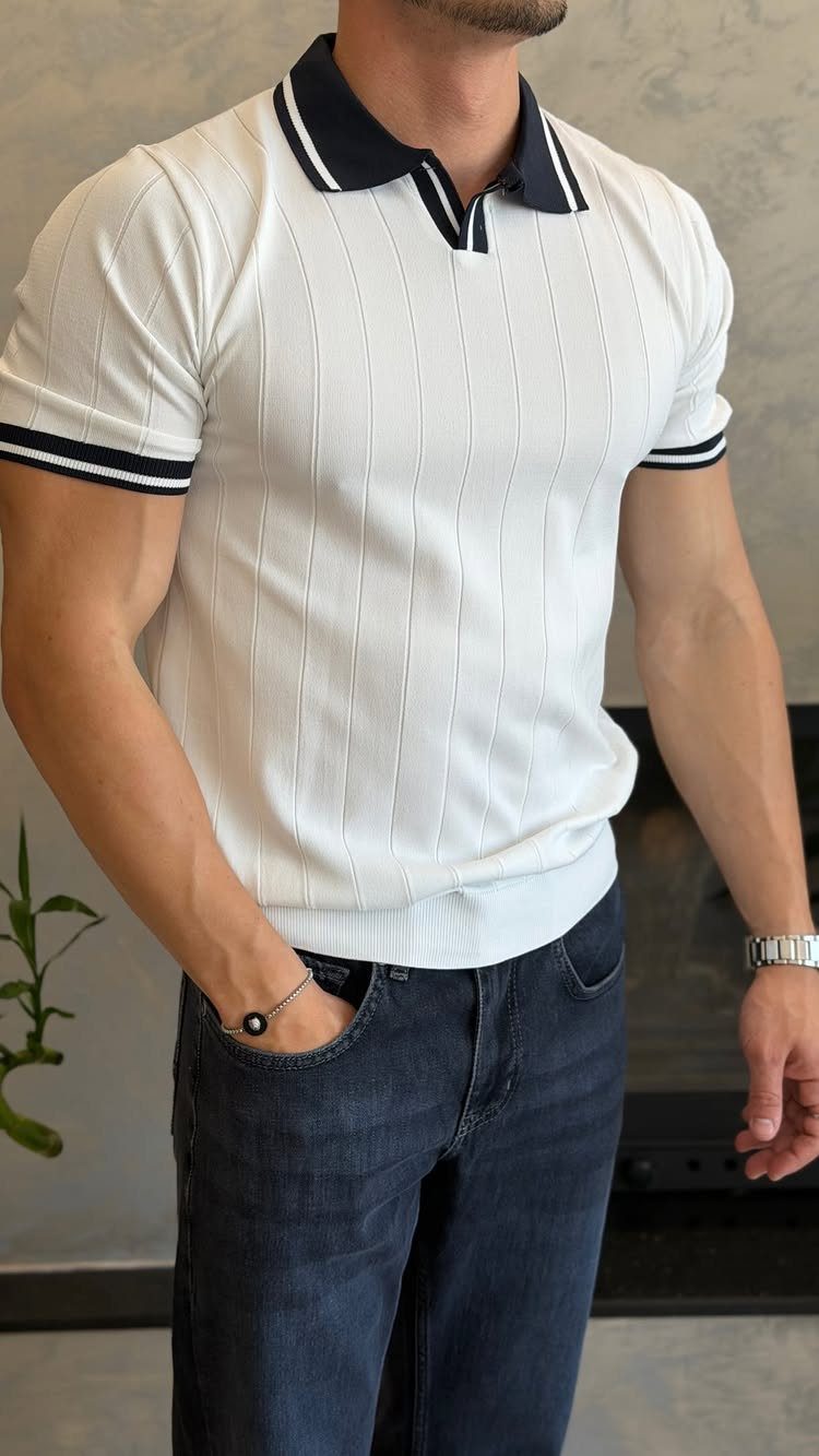Man wearing a white striped polo shirt with navy trim and dark blue jeans.