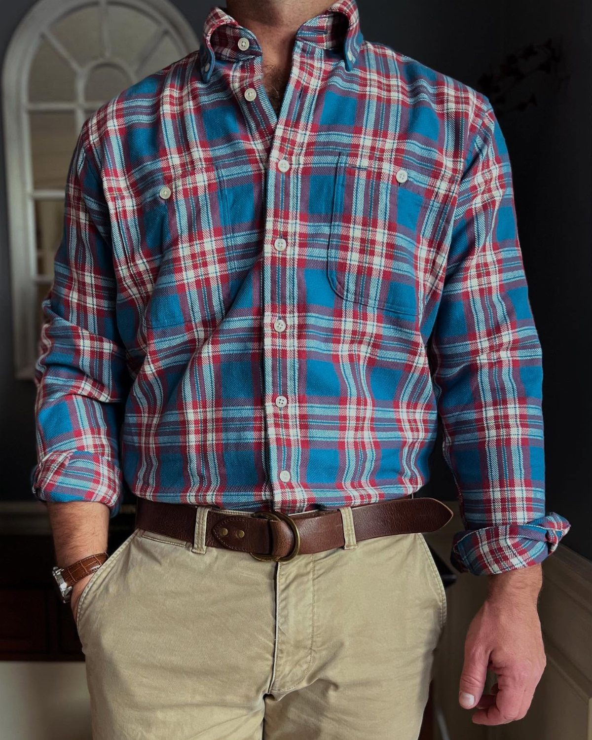 Man wearing a blue and red plaid flannel shirt and tan khaki trousers.