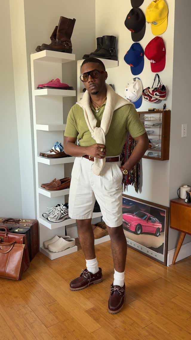 A man posing in a green polo, white shorts, and dark brown boat shoes.