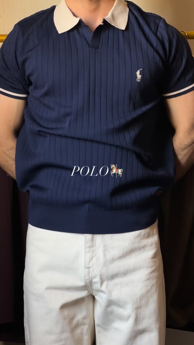 Man wearing a navy blue ribbed polo shirt with a white collar and white shorts.