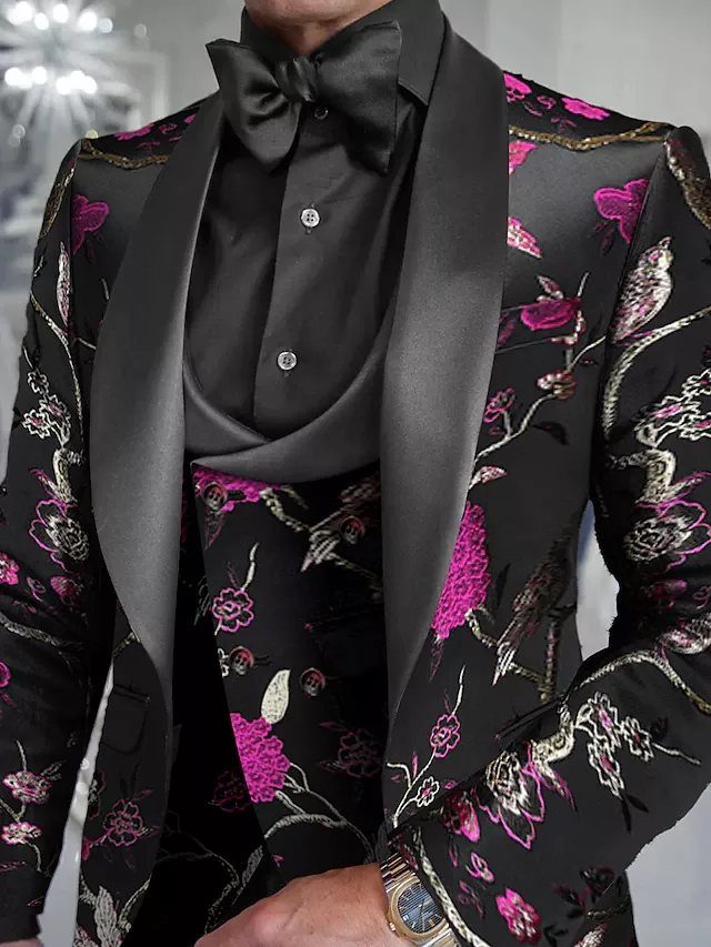 Man wearing a black suit with vibrant pink and white floral embroidery and a black bow tie.