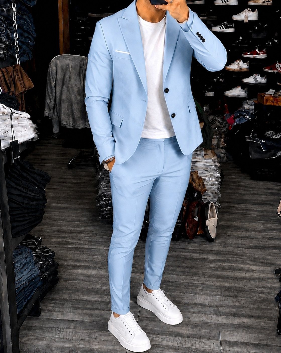 Man posing in a light blue suit with a white t-shirt and white sneakers.