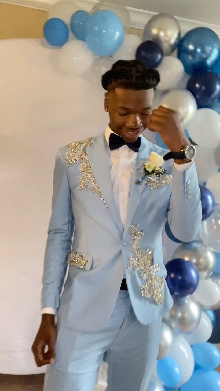 Young man smiling in a light blue suit with silver sequin embellishments and a black bowtie.
