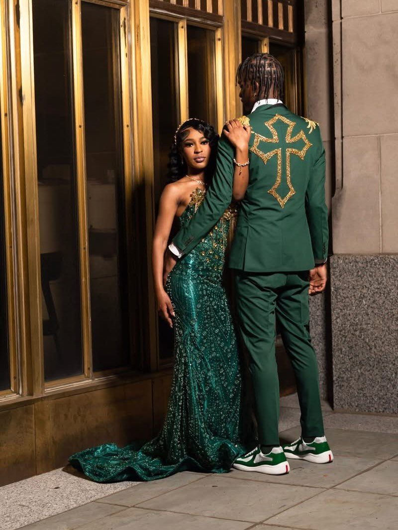 A man in an emerald green suit with a gold cross on the back and a woman in a green sequined dress.