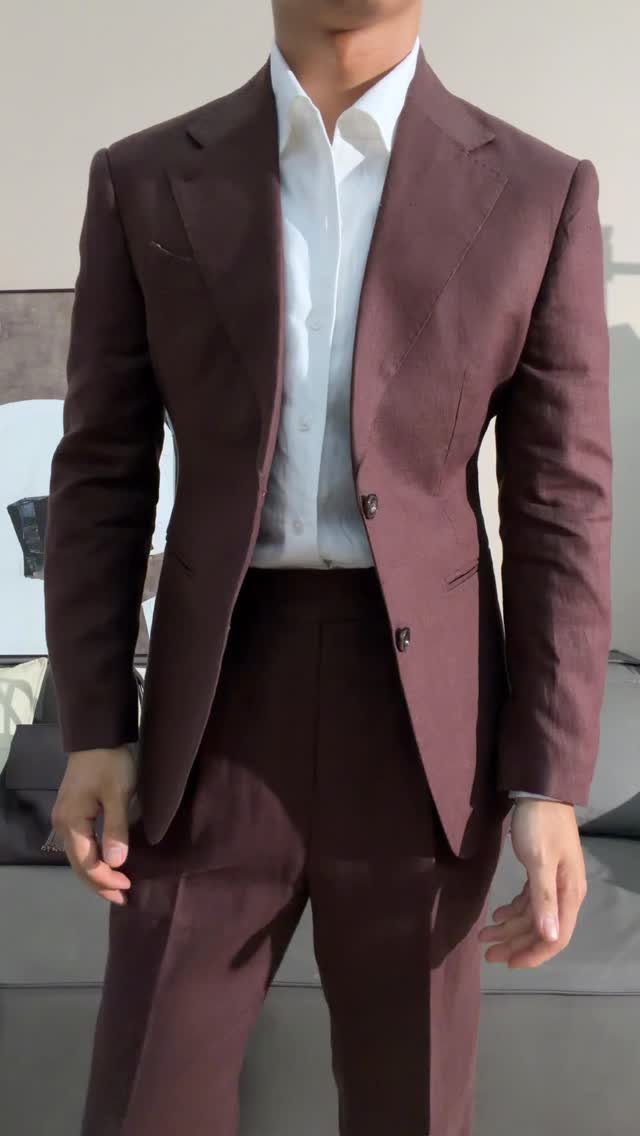 Man wearing a fitted burgundy suit and a white dress shirt standing indoors.