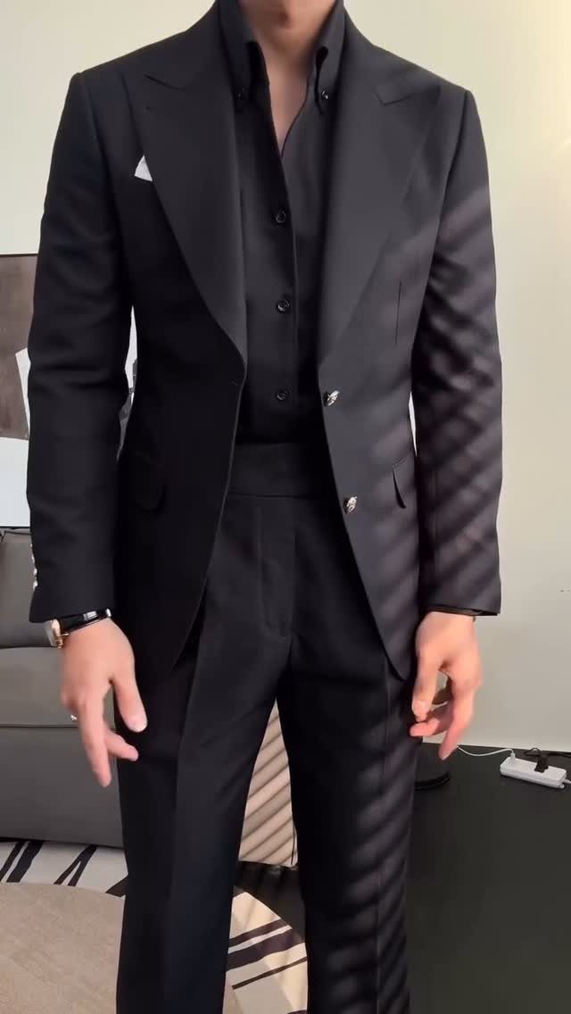 Man wearing a sleek black slim-fit blazer with a white pocket square and matching trousers.