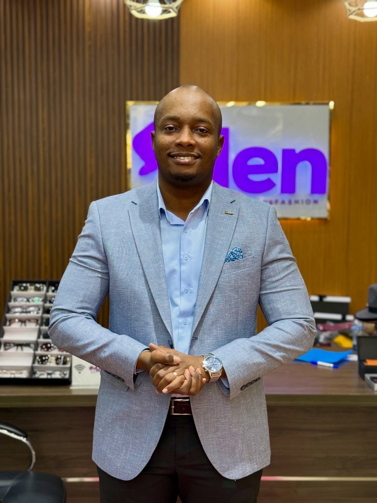Man smiling while wearing a light blue slim-fit blazer and a patterned pocket square.