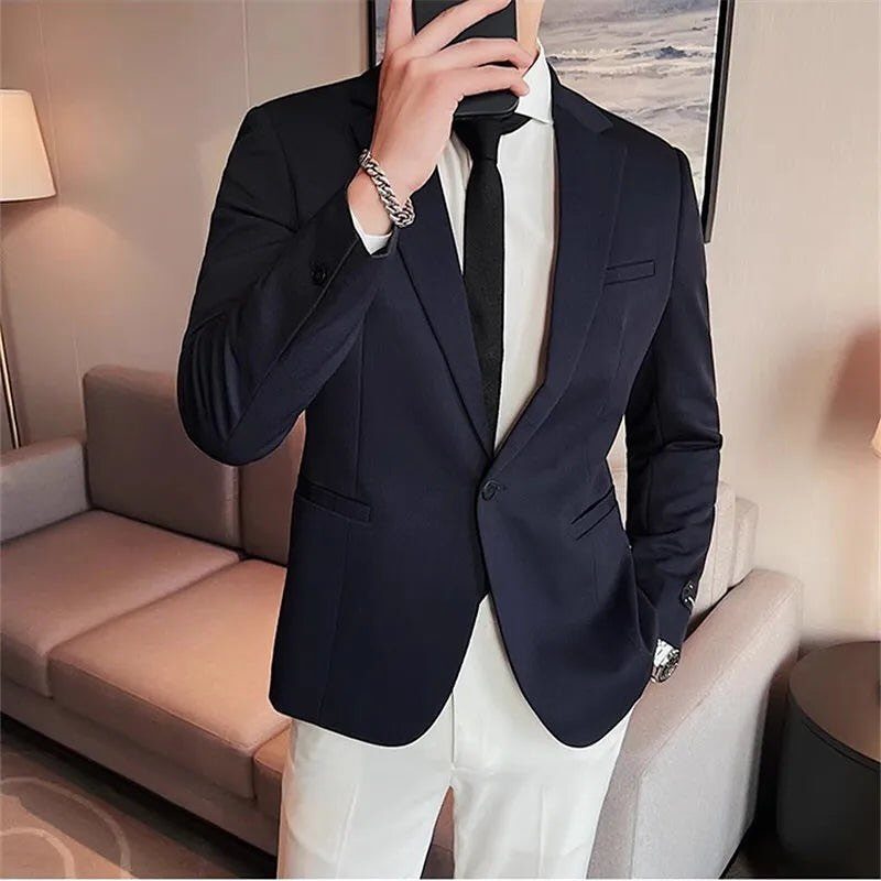 Man wearing a navy slim-fit blazer, white shirt, black tie, and white trousers.
